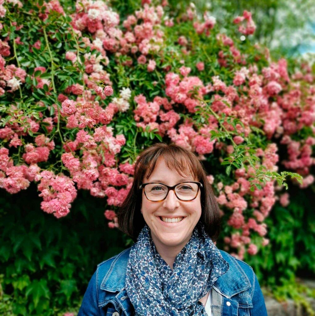 photo de profil avec des fleurs roses en arrière plan. Photo de la fondatrice, graphiste spécialisée en identité visuelle de l'atelier Filigrane